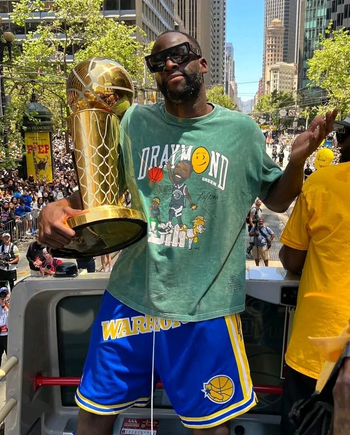 Golden State Warrior Draymond Green shrugs wryly while holding the championship trophy while riding along in his party bus on San Francisco’s Market Street on Monday. Twitter photo.