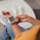 Unrecognizable woman measures her blood pressure using a wrist monitor in her cozy living room.