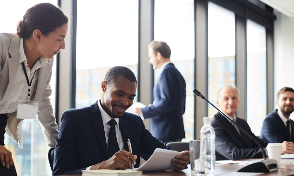 Business lady giving advices to black colleague with papers