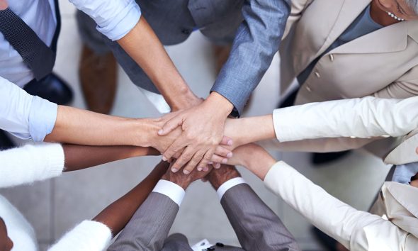 Shot of a group of coworkers with their hands in a huddle