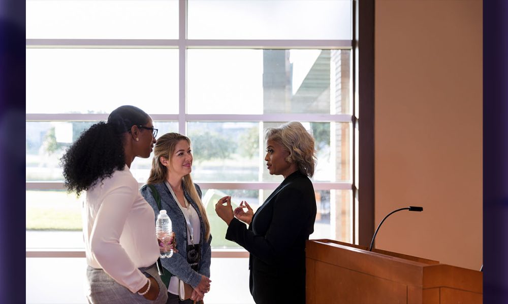 Mature female business conference keynote speaker talks with interested businesswomen after conference.