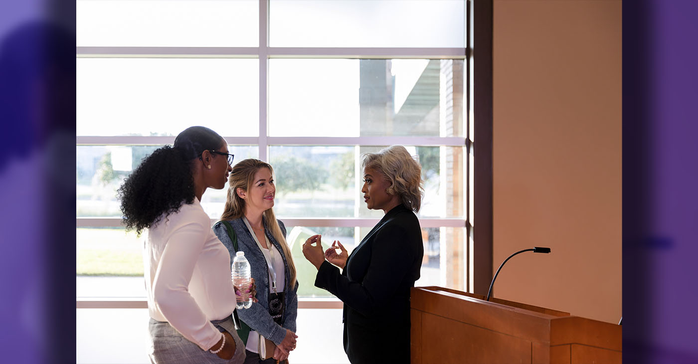 Mature female business conference keynote speaker talks with interested businesswomen after conference.