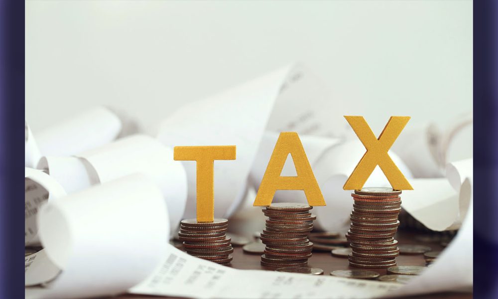 Word tax put on stacked coins and bills on the wooden table