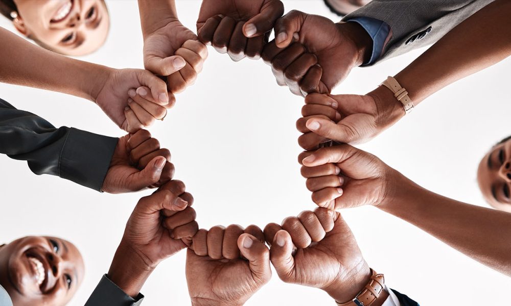 Hands, collaboration and motivation with a business team in a huddle with fists and a mindset of company vision. Mission, teamwork and goal with a group in a circle ready for growth and development