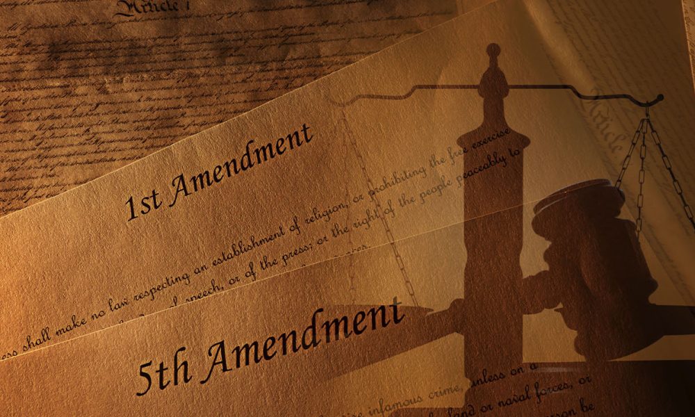 The First and Fifth Amendments and pages of the US Constitution with legal gavel and scales of justice