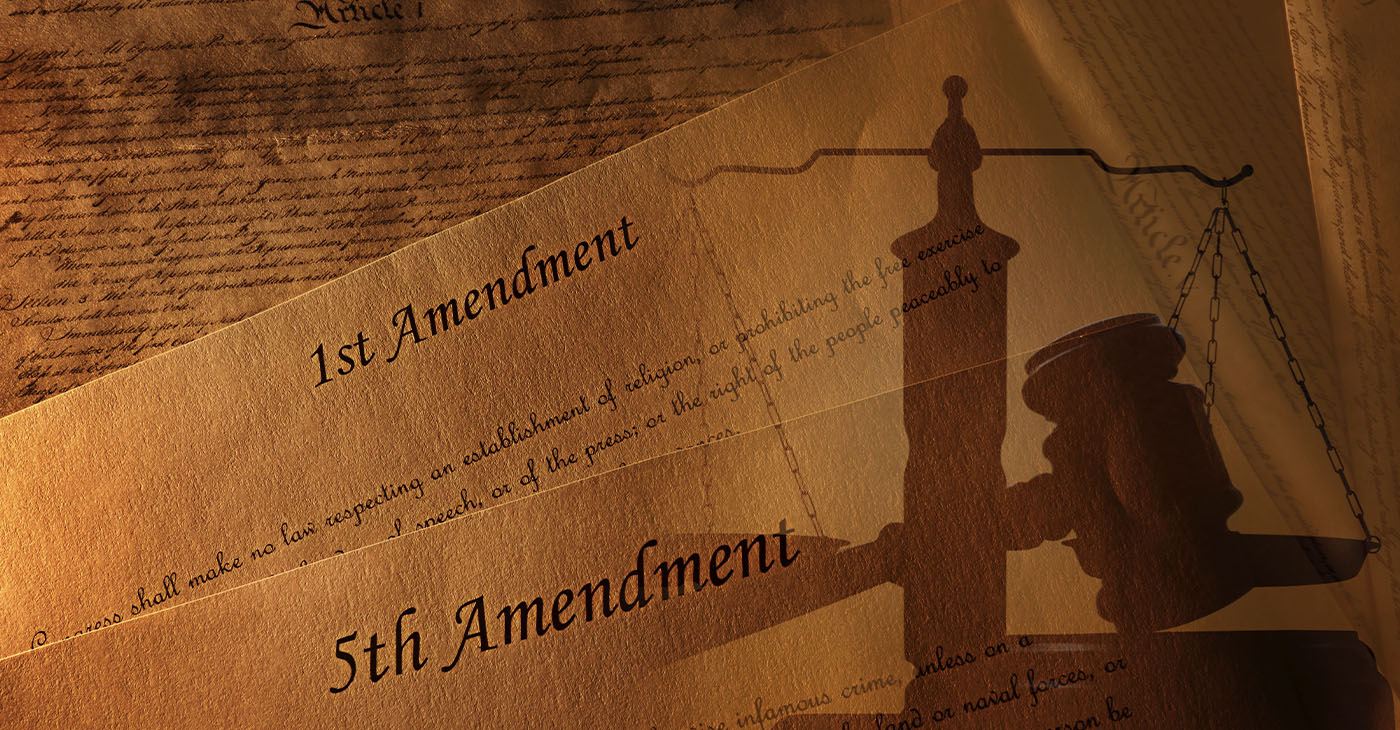 The First and Fifth Amendments and pages of the US Constitution with legal gavel and scales of justice