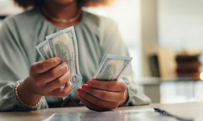 Business woman, hands or counting with cash for finance, profit or salary increase at office desk. Female person, accountant or employee with paper bills, financial savings or investment at workplace (Photo by Jacob Wackerhausen)