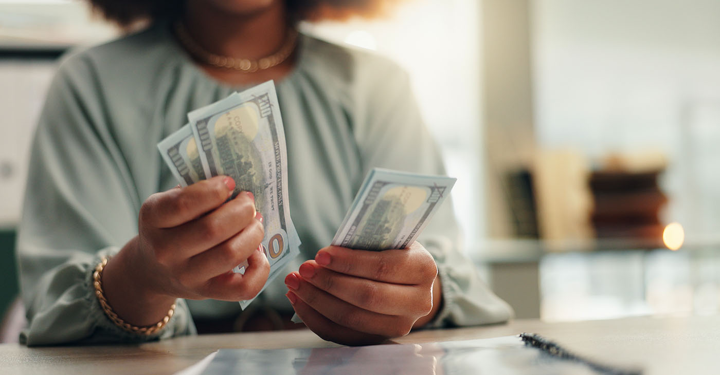 Business woman, hands or counting with cash for finance, profit or salary increase at office desk. Female person, accountant or employee with paper bills, financial savings or investment at workplace (Photo by Jacob Wackerhausen)
