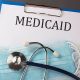 Folder with paper text MEDICAID , on a table with a stethoscope and medical masks, medical (Photo by Iryna Drozd)