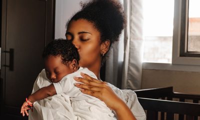 Young adult mother holding and kissing her newborn. (Photo by Djavan Ridriguez)