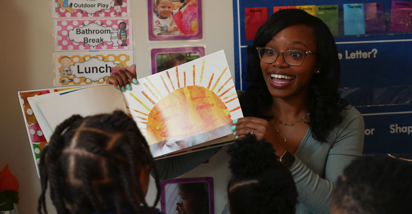 Shalicia Jackson reads a book to children at Modern Early Learning Academy, her family childcare home in Winston-Salem. Photo by: Liz Bell, EdNC