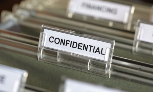 Inside of a filing cabinet with green folders and focus on confidential label (Photo by Brian A Jackson)
