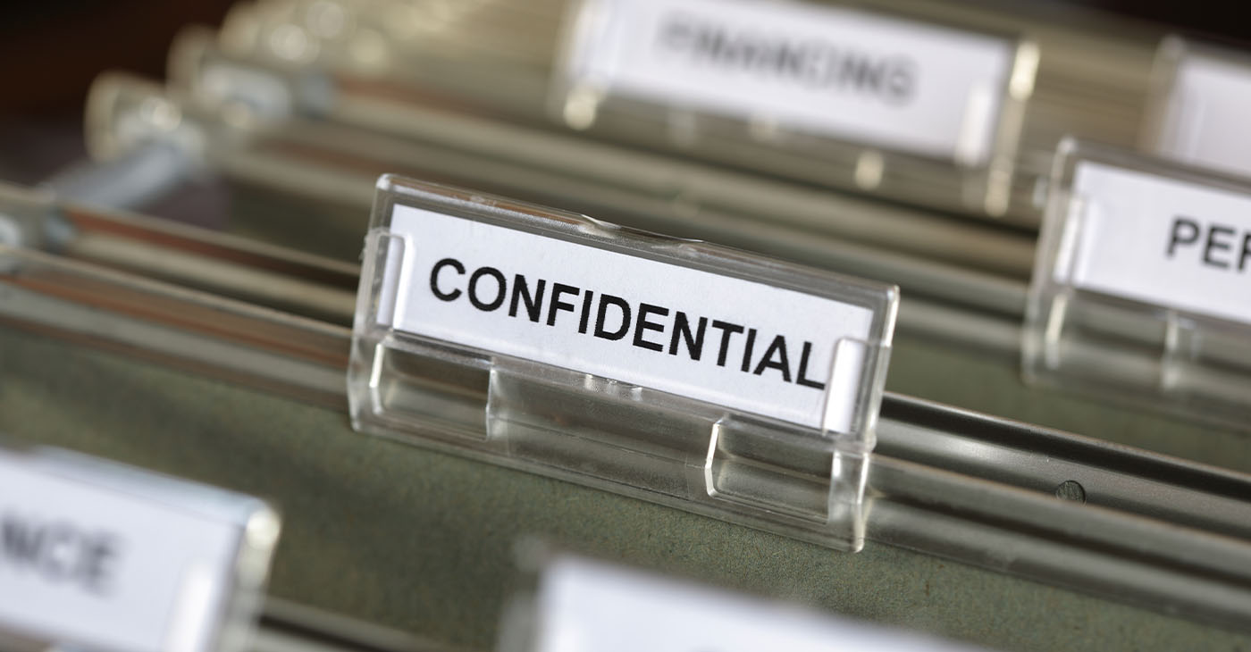 Inside of a filing cabinet with green folders and focus on confidential label (Photo by Brian A Jackson)