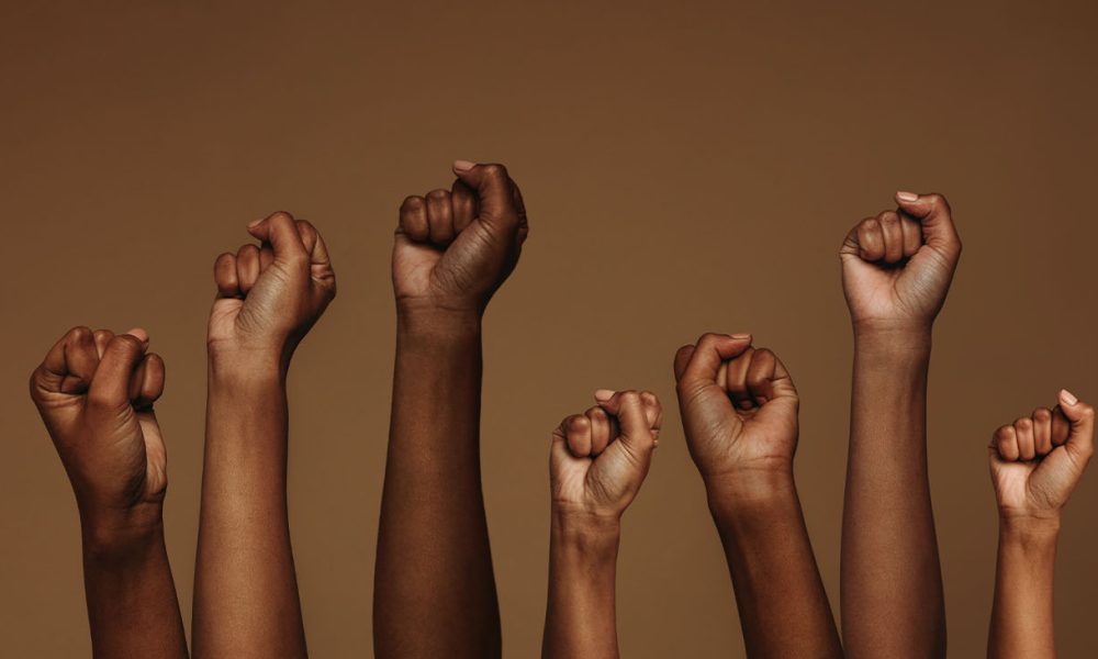 Cropped shot of hands raised with closed fists. Multiple hands raised up with closed fist symbolizing the protests movement. (Photo by Jacob Lund