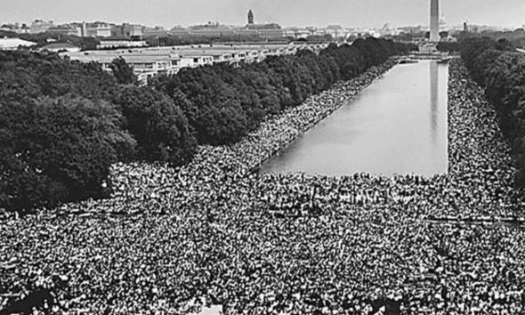 View of the crowd at 1963 Civil Rights March on Washington, D.C. A wide-angle view of marchers along the mall, showing the Reflecting Pool and the Washington Monument. (Wikimedia Commons / Photo by U.S. Information Agency, Press and Publications Service)
