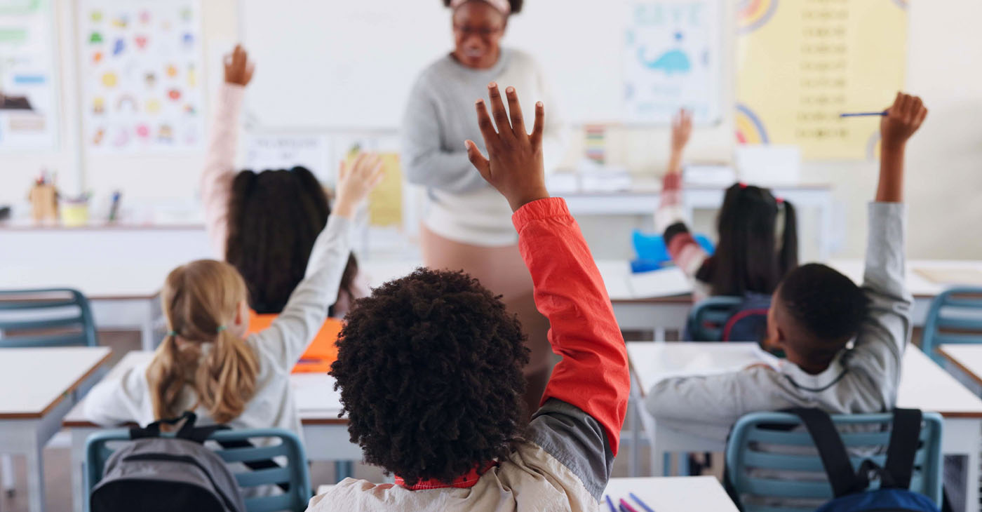 Children, back and hands raised at school with for question, answer and learning at youth academy. Kids, education and teacher for development with sign for talking, quiz and scholarship in classroom (Photo b Jacob Wackerhausen)