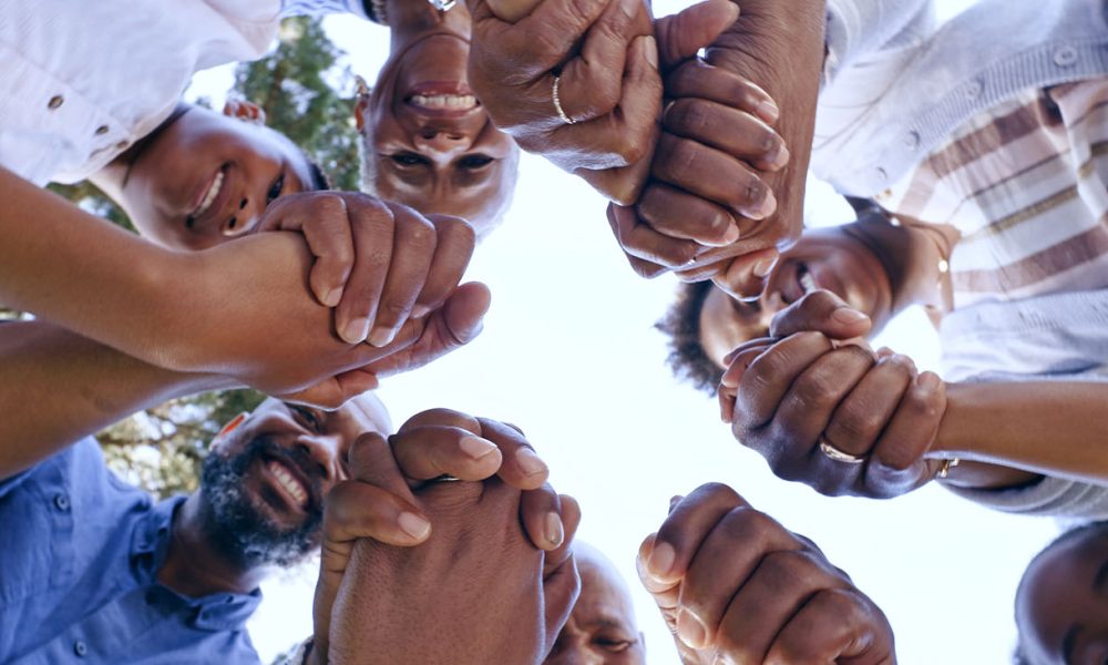 Holding hands, community support or family in nature for bonding or playing in a park together. (Photo by Jacob Wackerhausen)