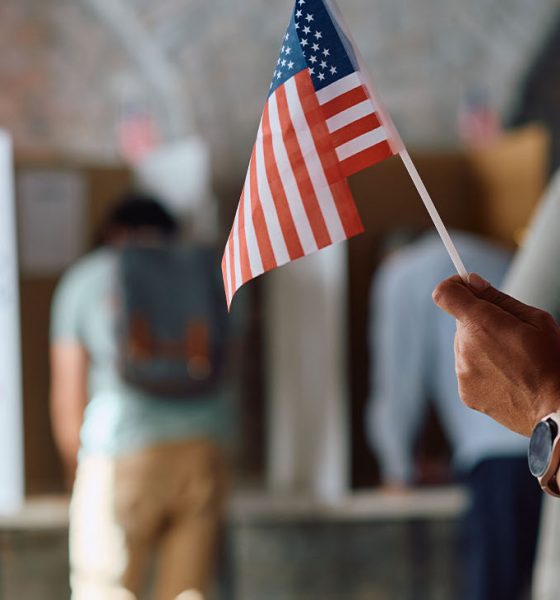Close up of African American voter with national flag in waiting line during US elections. (Photo by Drazen Zigic)