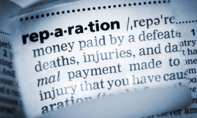 The Dictionary definition of the word “reparation” photo taken through magnifying glass from a page of a dictionary with selective focus.