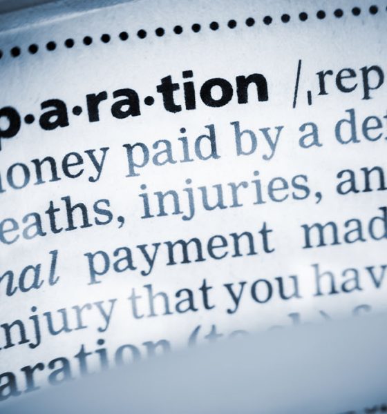 The Dictionary definition of the word “reparation” photo taken through magnifying glass from a page of a dictionary with selective focus.