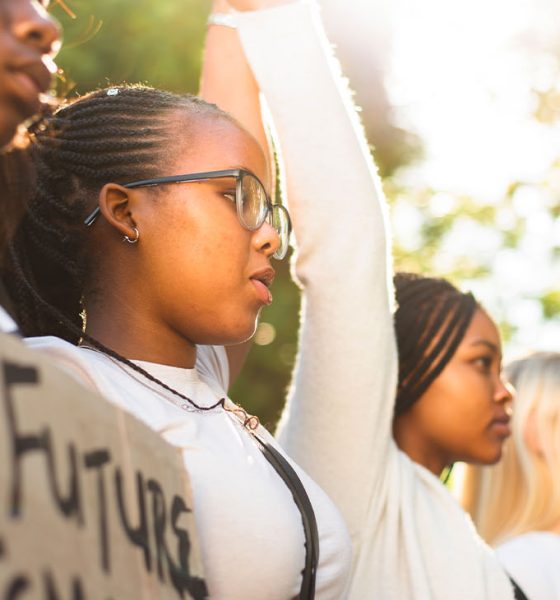 Diverse group of teenage girls holding hands in unity and holding up protest signs during a women's rights march (Photo by Nicky Lloyd)