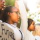 Diverse group of teenage girls holding hands in unity and holding up protest signs during a women's rights march (Photo by Nicky Lloyd)