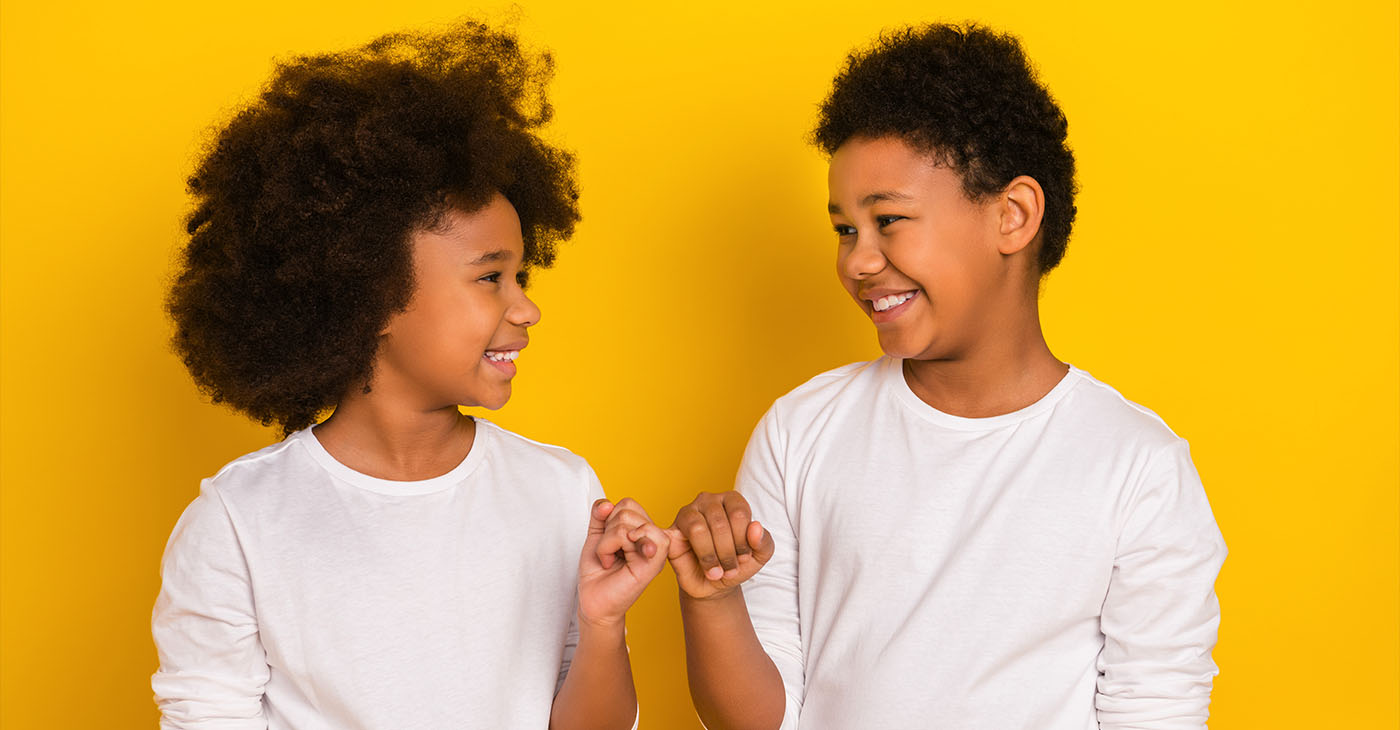 Photo of sweet friendly schoolboy schoolgirl wear white shirts holding small fingers isolated yellow color background.