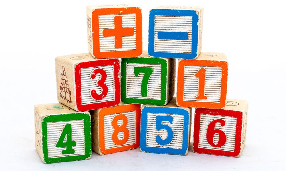Wooden blocks with numbers and plus & minus sign isolated on white background. Maths learning concept.
