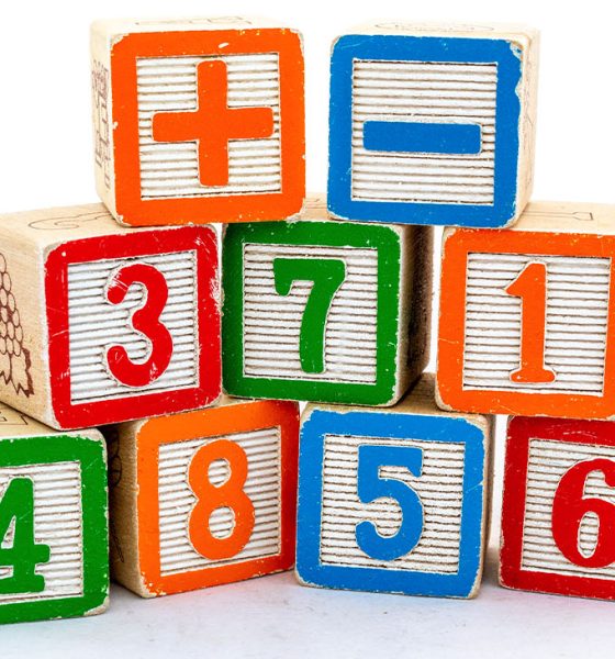 Wooden blocks with numbers and plus & minus sign isolated on white background. Maths learning concept.