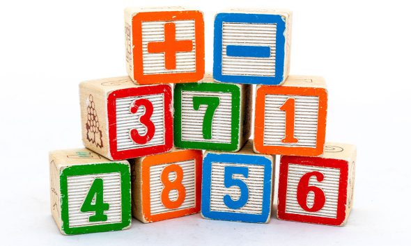 Wooden blocks with numbers and plus & minus sign isolated on white background. Maths learning concept.