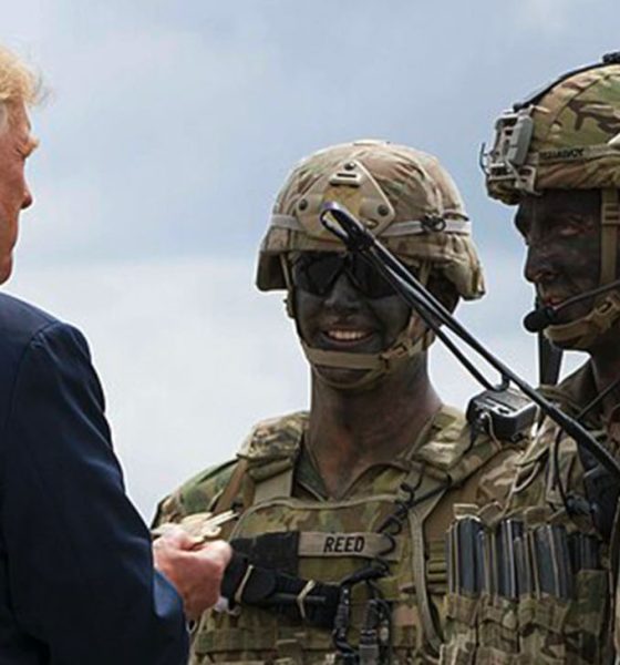 President Donald J. Trump is presented with a 10th Combat Aviation Brigade challenge coin following an air assault and gun rain demonstration at Fort Drum, New York, on August 13. The demonstration was part of President Trump's visit to the 10th Mountain Division (LI) to sign the National Defense Authorization Act of 2019, which increases the Army's authorized active-duty end strength by 4,000 enabling us to field critical capabilities in support of the National Defense Strategy. (U.S. Army photo by Sgt. Thomas Scaggs) 180813-A-TZ475-010 (Wikimedia Commons / Photo by U.S. Army photo by Sgt. Thomas Scaggs)
