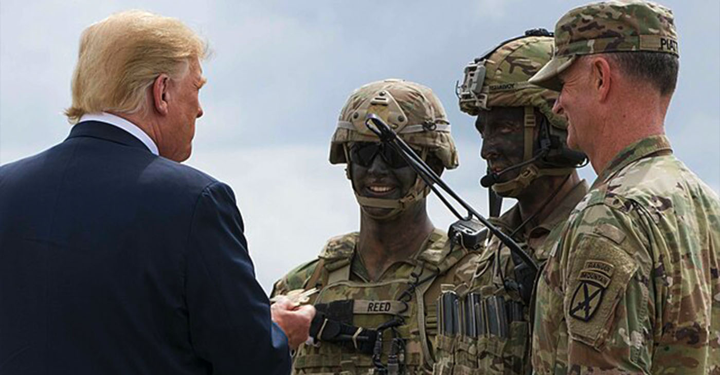 President Donald J. Trump is presented with a 10th Combat Aviation Brigade challenge coin following an air assault and gun rain demonstration at Fort Drum, New York, on August 13. The demonstration was part of President Trump's visit to the 10th Mountain Division (LI) to sign the National Defense Authorization Act of 2019, which increases the Army's authorized active-duty end strength by 4,000 enabling us to field critical capabilities in support of the National Defense Strategy. (U.S. Army photo by Sgt. Thomas Scaggs) 180813-A-TZ475-010 (Wikimedia Commons / Photo by U.S. Army photo by Sgt. Thomas Scaggs)