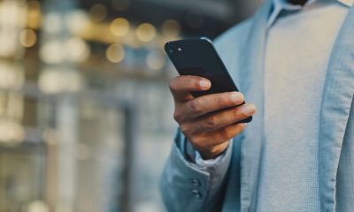 Travel businessman hand with phone in city typing and walking, networking or on 5g mobile app in New York. Street, employee or worker on smartphone for communication or commute to office building (Photo by Layla Bird)