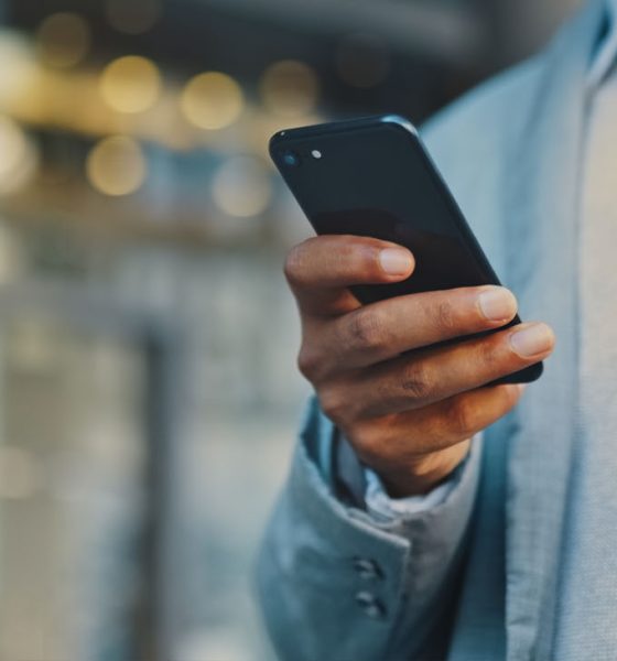Travel businessman hand with phone in city typing and walking, networking or on 5g mobile app in New York. Street, employee or worker on smartphone for communication or commute to office building (Photo by Layla Bird)