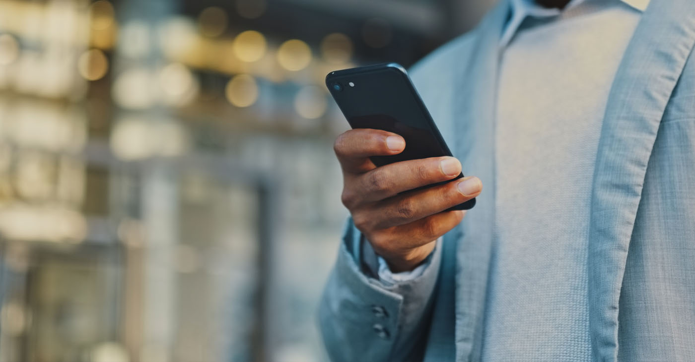 Travel businessman hand with phone in city typing and walking, networking or on 5g mobile app in New York. Street, employee or worker on smartphone for communication or commute to office building (Photo by Layla Bird)