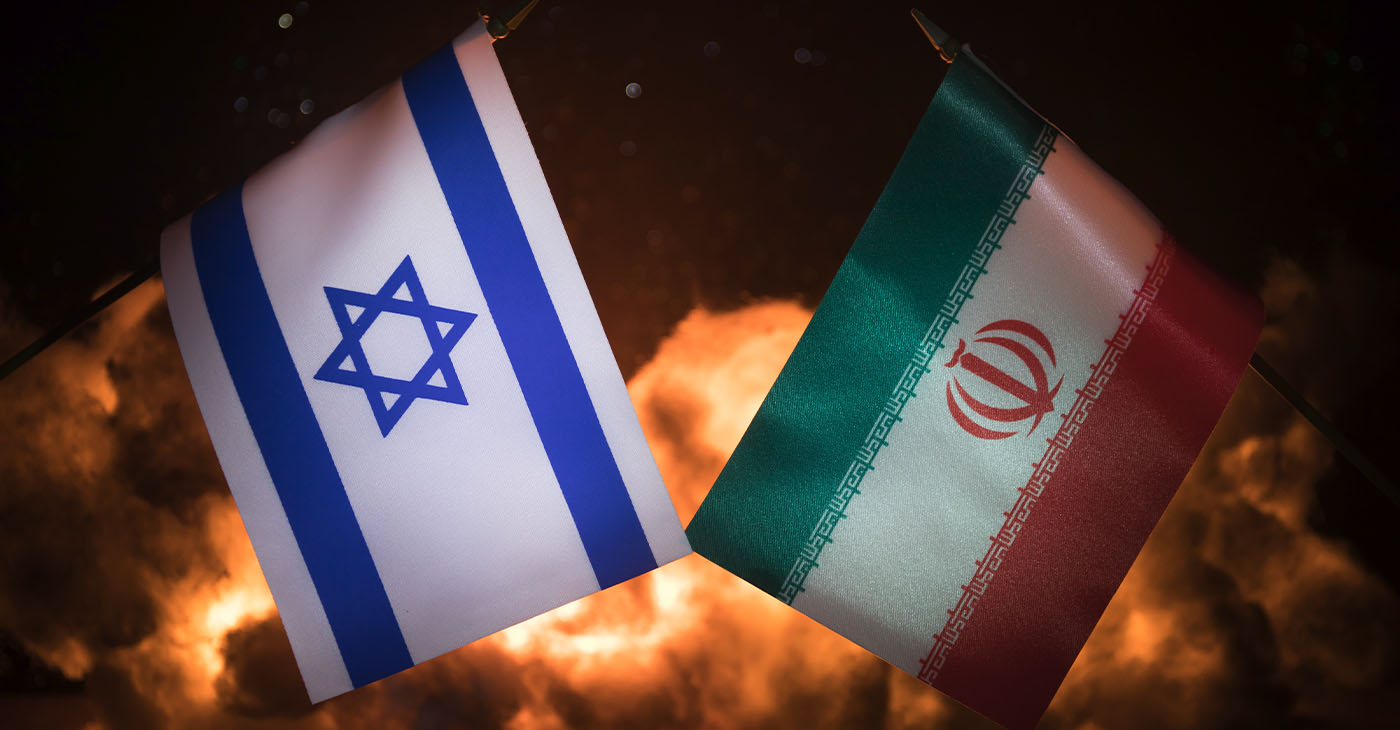 Israel and Iran small flags on burning dark background. Concept of crisis of war and political conflicts between nations. Selective focus (Photo by Zeferli)