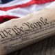 United States constitution with American flag in background on rustic wooden table