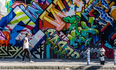 New York City, NY, USA - October 1, 2013: Hipster male walking next to a wall of graffiti in Brooklyn, New York, US.