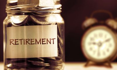Close up Coins in glass jar with alarm clock for time to money saving for retirement concept , vintage color tone