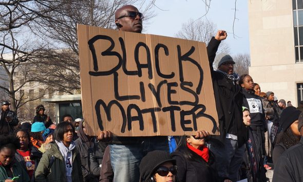 Washington DC, USA-December 13, 2014: This man is protesting police brutality at a protest led by Reverend Al Sharpton on Pennsylvania Avenue in Washington DC. He displays a sign with the message Black Lives Matter. Recently the deaths of Michael Brown, Eric Garner and Tamir Rice have upset the black community.