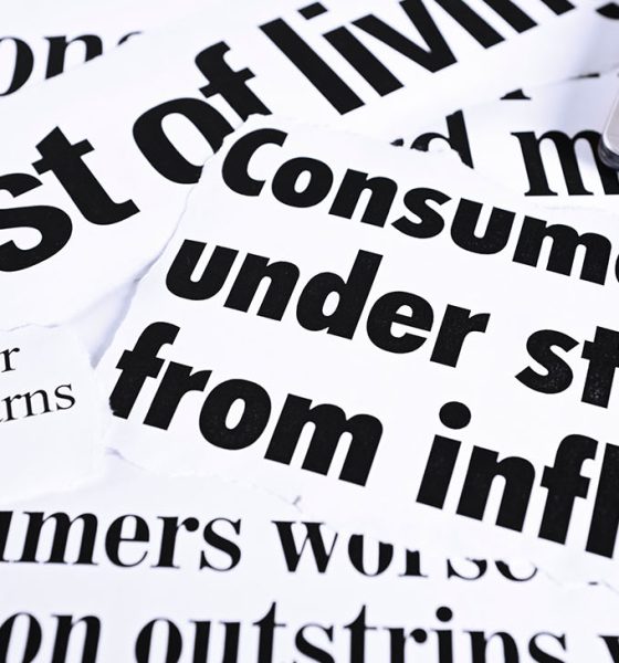 Calculator on newspaper headlines about cost of living and inflation