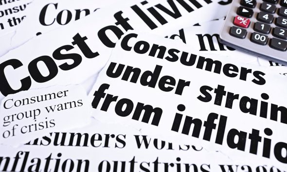 Calculator on newspaper headlines about cost of living and inflation