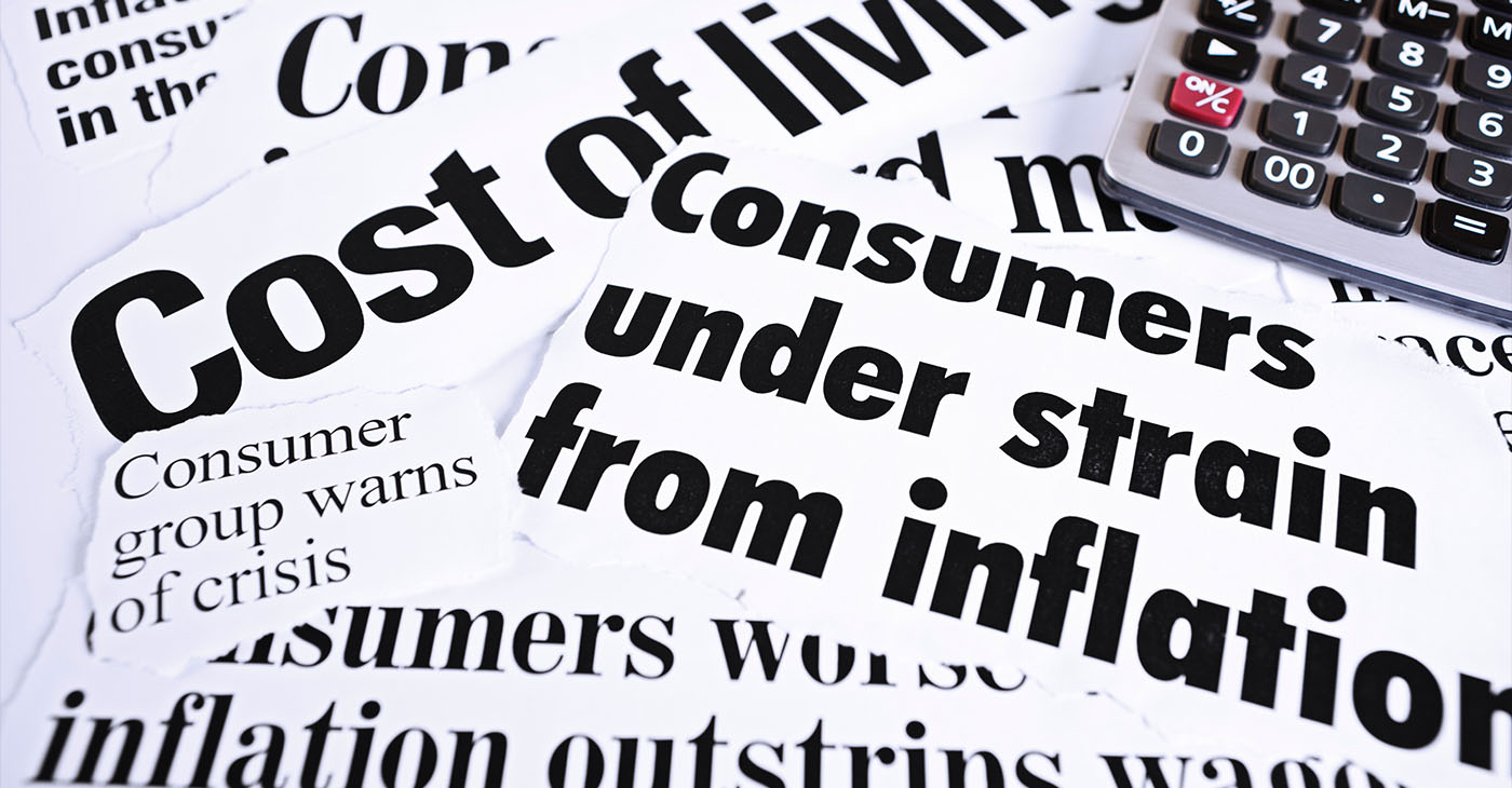 Calculator on newspaper headlines about cost of living and inflation