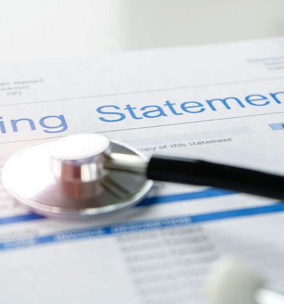 Health care billing statement with stethoscope, bottle of medicine for doctor's work in medical center stone background.