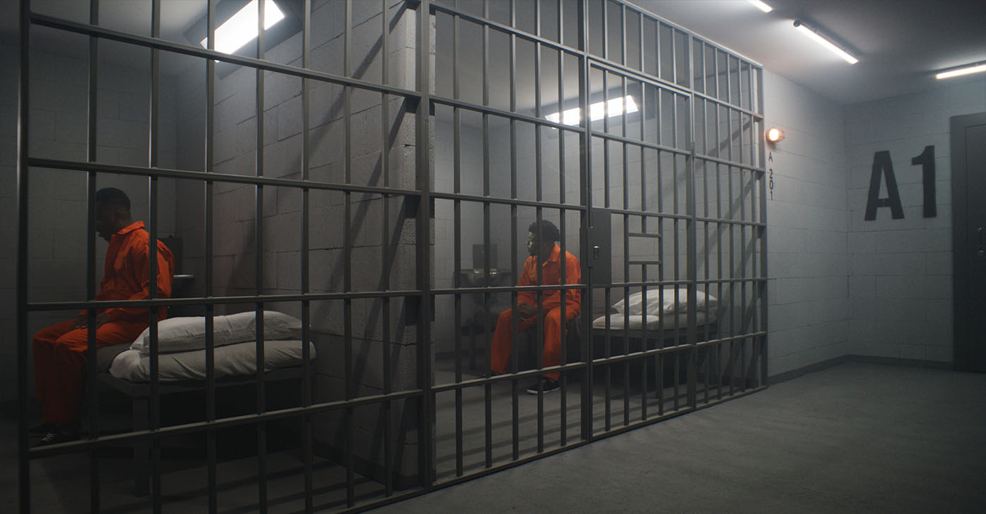African American inmates in detention center or correctional facility. Depressed man in orange uniform sits on prison bed and looks at barred window. Prisoners serve imprisonment term in jail cell.