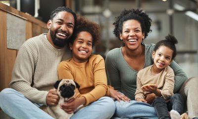 Happy parents with their girls and a dog spending time at home.