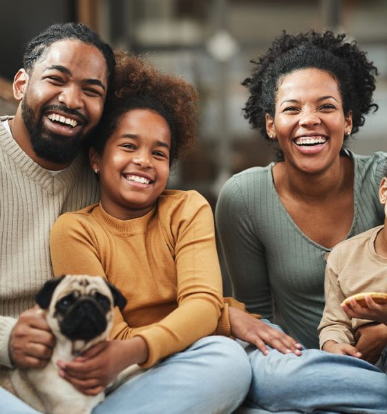 Happy parents with their girls and a dog spending time at home.