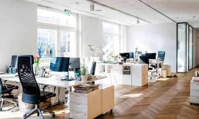 Still life shot of a modern coworking office space. Spacious workplace with desks and computer. (Photo by Portra)