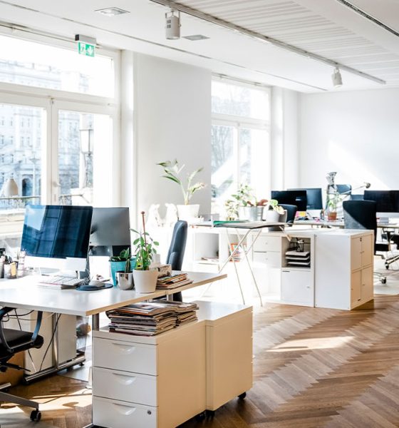 Still life shot of a modern coworking office space. Spacious workplace with desks and computer. (Photo by Portra)