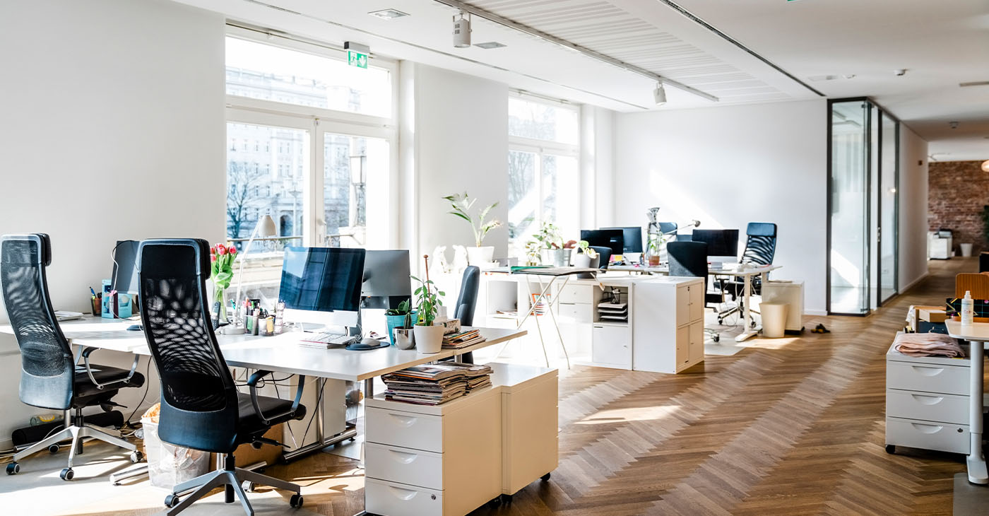Still life shot of a modern coworking office space. Spacious workplace with desks and computer. (Photo by Portra)